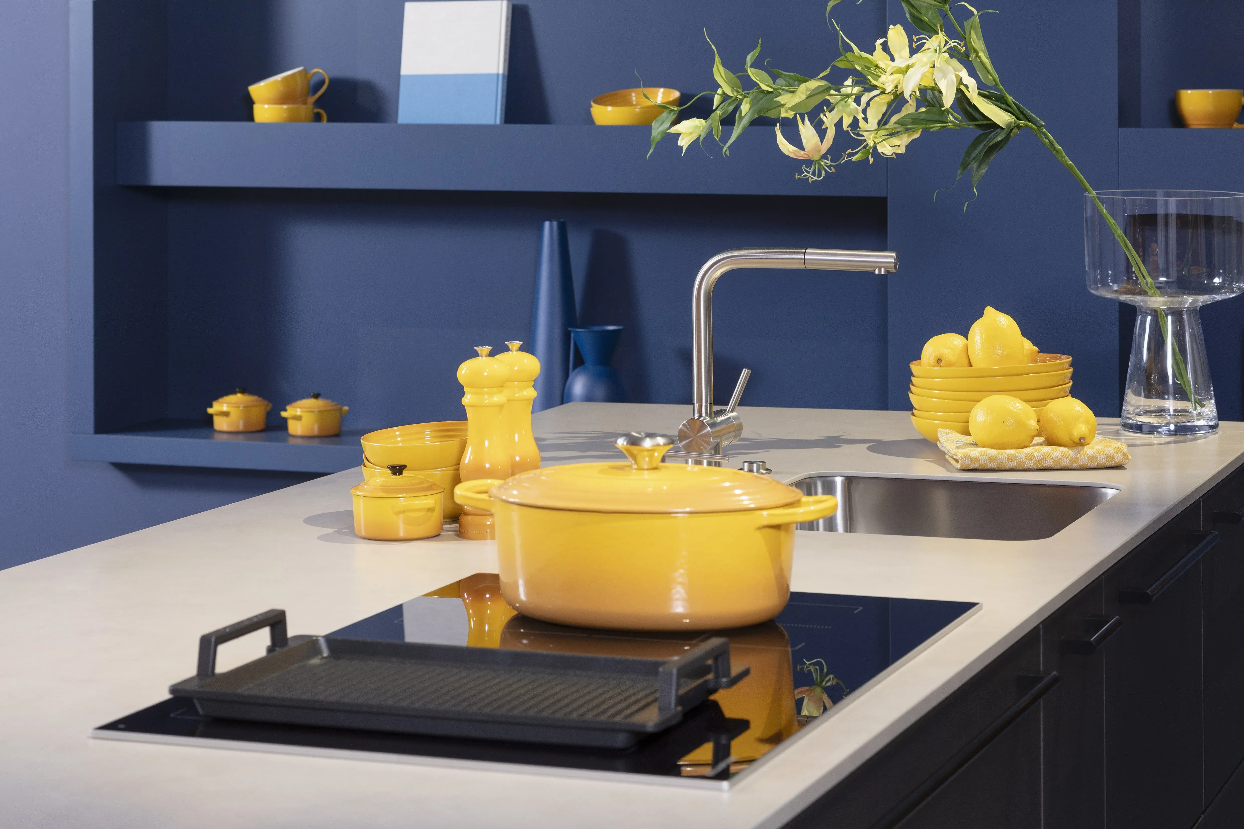 Concept130ART Front: SMART-GL Sandgrau metallic APL: SMART-GL Carbon metallic Geräte Blaupunkt Armatur und Spüle: Franke  Features: Insellösung mit Thekenfunktion mit Schubladen, Teppanyakiaufsatz für Kochfeld, Schubladen in Silber, Schubladen mit Griffmulde, Nischenlösung in Blau mit Regalfunktion.